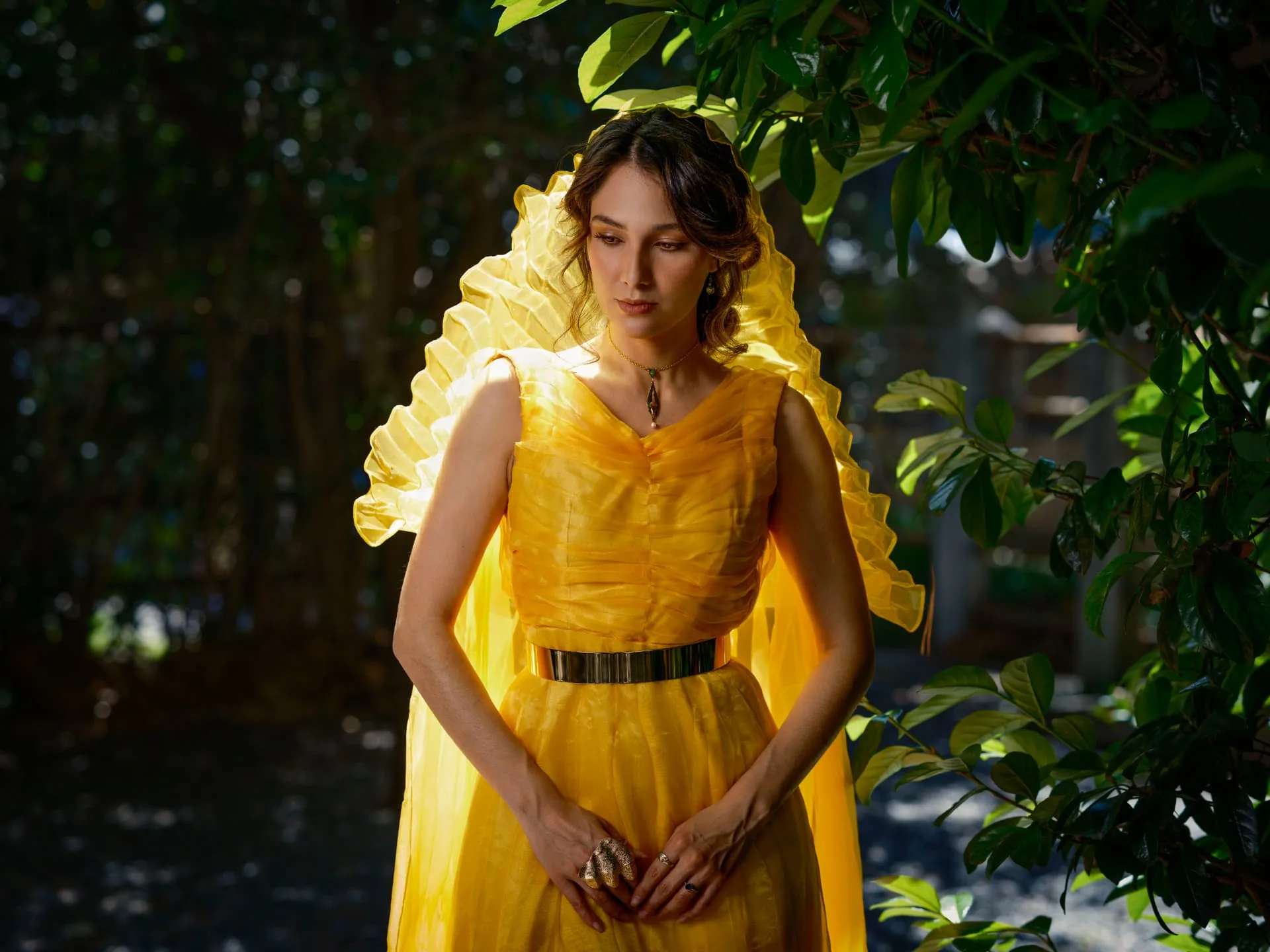 Celeste Lomelí con vestido amarillo entre la vegetación del jardín